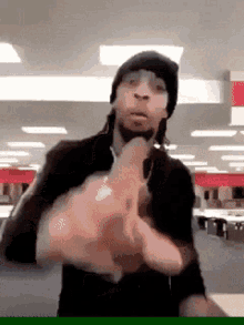 a man wearing a beanie and headphones is pointing at the camera