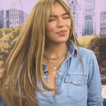 a woman wearing a denim shirt and a necklace with a heart on it