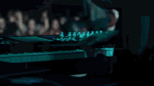 a blurry image of a person playing a keyboard with a crowd in the background