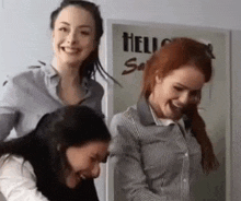 a group of three women are standing next to each other in front of a sign that says hello .
