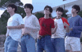 a group of young men standing next to each other with one wearing a red shirt