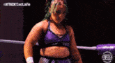 a female wrestler with green hair is standing in a ring .
