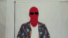 a man wearing a red balaclava and sunglasses is holding a hula hoop in front of his face