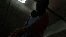 a person holding a bat in a dark room with a light behind them