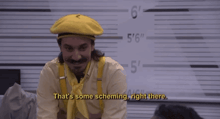 a man wearing a yellow hat and suspenders says " that 's some scheming right there "