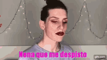 a woman with red lipstick and freckles is making a funny face while wearing a bun .