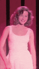 a woman in a white dress is smiling and dancing on stage