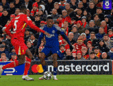 a soccer game is being played in front of a mastercard ad