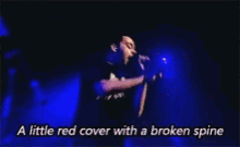 a man singing into a microphone with the words " a little red cover with a broken spine " above him
