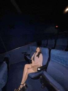 a woman sits on a blue seat in an empty auditorium