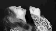 a black and white photo of a woman in a leopard print sweater laying down .