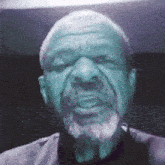 a man with a beard is looking at the camera with a serious look on his face