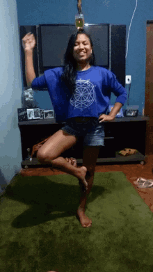 a girl wearing a blue shirt with a circle on it is standing on one leg