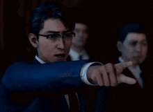 a man wearing glasses and a suit is pointing at something