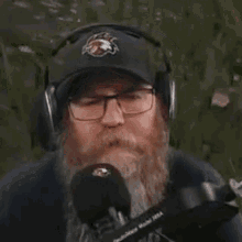 a man with a beard and glasses is talking into a microphone .
