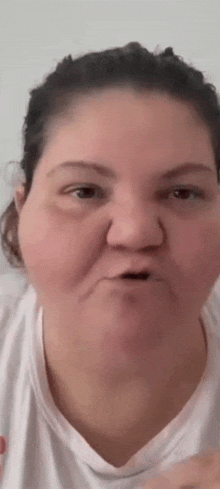 a woman is making a funny face while wearing a white t-shirt .