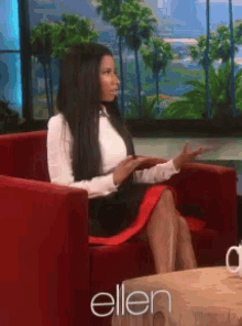 a woman sits in a red chair in front of a sign that says ellen on it