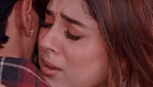 a close up of a woman 's face while a man hugs her .