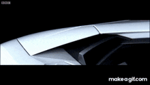 a white sports car is driving down a road with bbc written on the screen