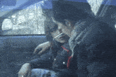 a boy smoking a cigarette in a car with another boy