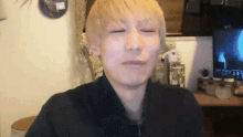 a man with blonde hair is making a face in front of a television