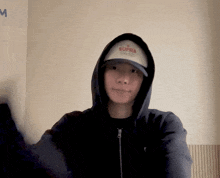 a man wearing a black hoodie and a supra hat