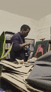 a man in a purple sweater is working on a painting in a room