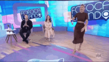 a woman is dancing on a stage in front of a sign that says " fofoca lando "