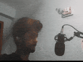 a man with a beard is singing into a microphone in a room