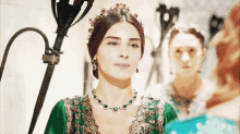 a woman wearing a tiara and a necklace with emeralds