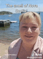 a woman stands in front of a body of water with the caption " the smell of nova scotia ! "