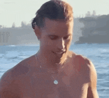 a shirtless man wearing a necklace is standing in the water .