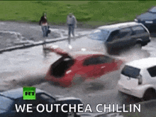 a red car is stuck in a puddle of water .