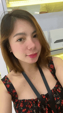 a woman wearing a black and red floral dress and a gold necklace