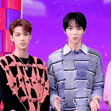 two young men are standing next to each other in front of a purple wall