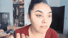 a woman with a bun on her head is applying makeup