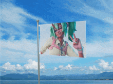 a flag flying in the wind with mountains in the background and the ocean in the foreground