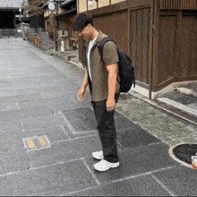 a man with a backpack stands on a sidewalk