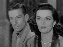 a man and a woman are standing next to each other and looking at the camera .
