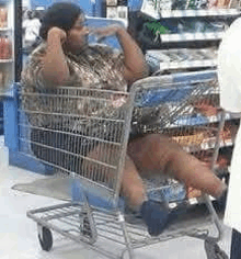 a man is sitting in a shopping cart with his legs crossed in a store .