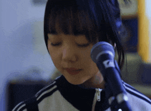 a close up of a woman singing into a microphone with the letter a on it