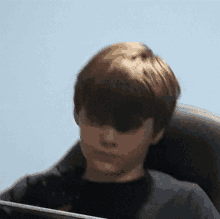 a young boy in a black shirt is sitting in a chair looking at a tablet