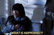 a man is sitting on a couch and says what is happening