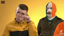 a man in a yellow jacket is standing next to another man in a knitted mask with the irish flag on it