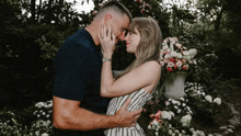 a man and woman are kissing in front of flowers in a garden