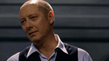 a bald man wearing a vest and striped shirt