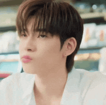 a close up of a young man 's face with a white shirt and earrings .