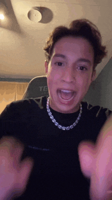 a young man wearing a black shirt and a necklace with letters on it