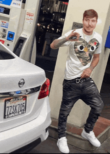 a man standing next to a white car with a hilltop license plate