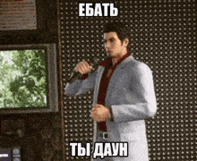 a man in a suit is singing into a microphone in front of a tv .